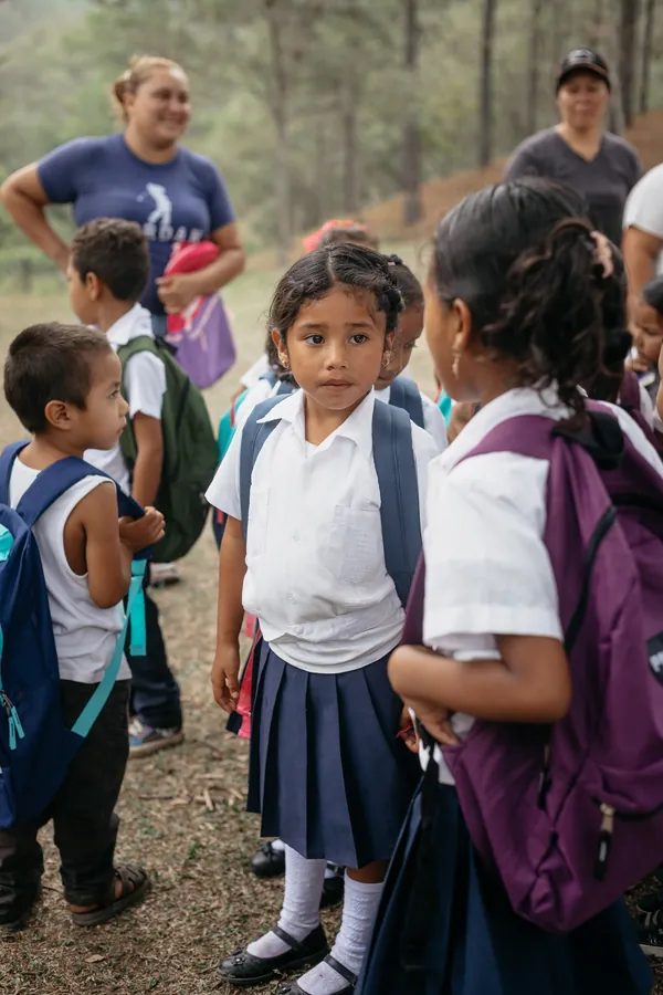 Bambina in divisa scolastica con il nuovo zaino durante un'attività di Nissi Project